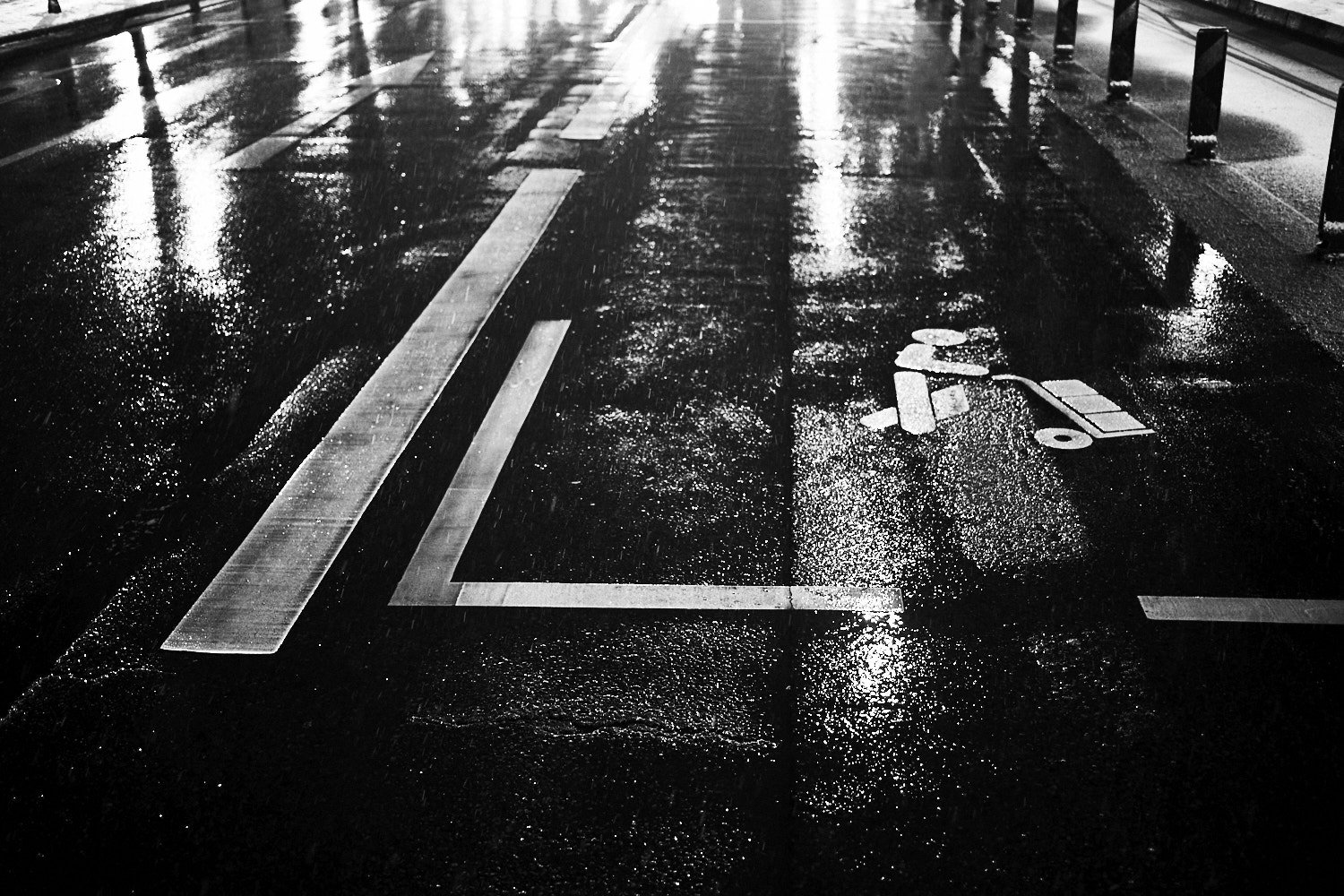 Nasse Straße in Berlin Schöneberg nach Regen mit Pfützen und Metallschienen, Schwarz-Weiß-Fotografie