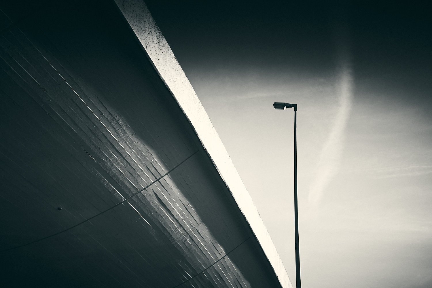 Street lamp against concrete highway bridge with dramatic sky in Berlin Wilmersdorf